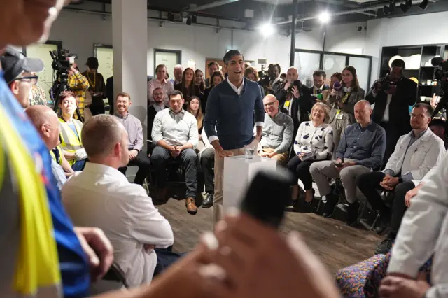 Sunak smiles as he speaks in front of a crowd at a pottery factory