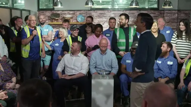 Sunak speaking to voters. Keith is standing in a high vis vest, holding a microphone.