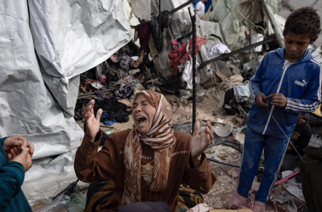 A woman reacts as people inspect their tents after an Israeli strike in Rafah