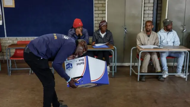 An Independent Electoral Commission (IEC) official seals a ballot box using his teeth while setting up the Hitekani Primary School polling station in Soweto on May 29, 2024, during South Africa's general election.