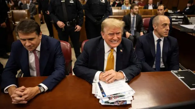 Donald Trump (C) sits at the defence table with a stack of notes in a New York courtroom, flanked on either side by his lawyers