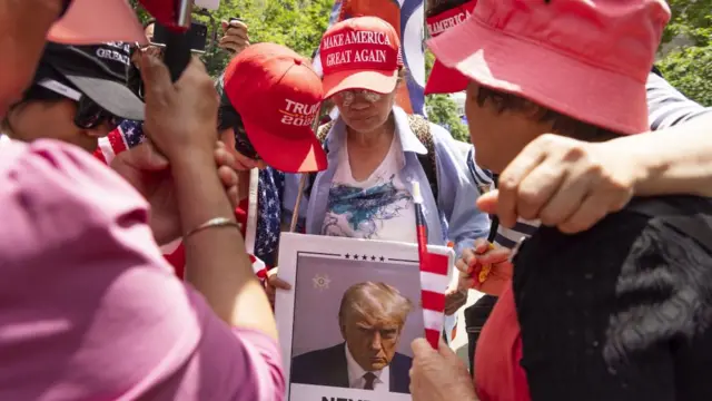 Supporters of former US President Donald Trump hold a prayer circle in a park across the street from the courthouse