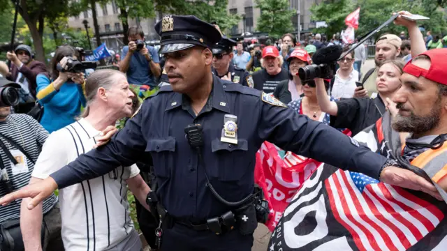 An NYPD officer separates supporters of Republican presidential candidate and former U.S. President Donald Trump and an activist advocating for Trump to be convicted, outside the Manhattan criminal court during jury