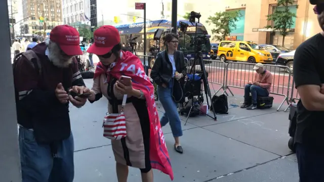 Trump supporters where Make America Great Again hats and capes are standing outside Trump Tower