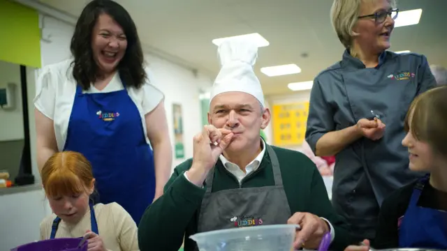 Ed Davey and two schoolchildren baking