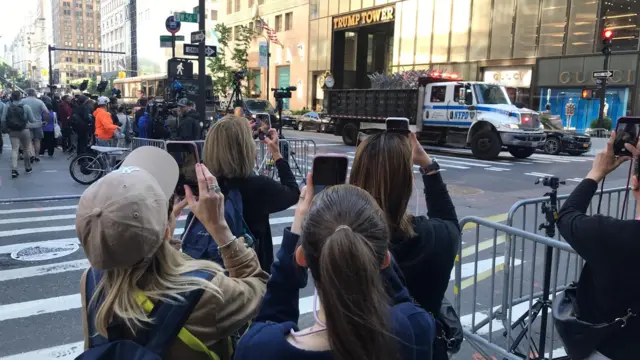 People standing outside Trump Tower take pictures with their phones