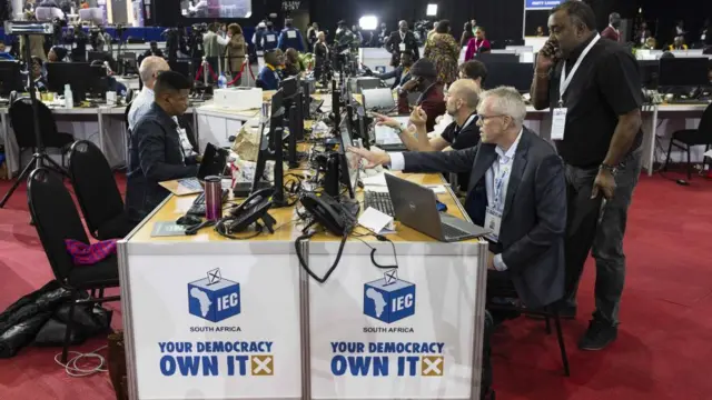 People stand around monitors as results come in