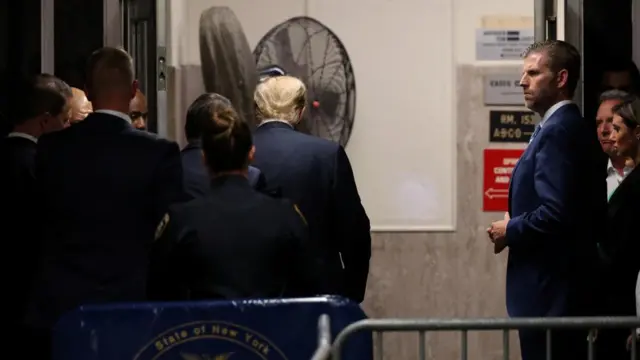 Donald Trump walks away from a press conference outside the Manhattan courtroom with his security team