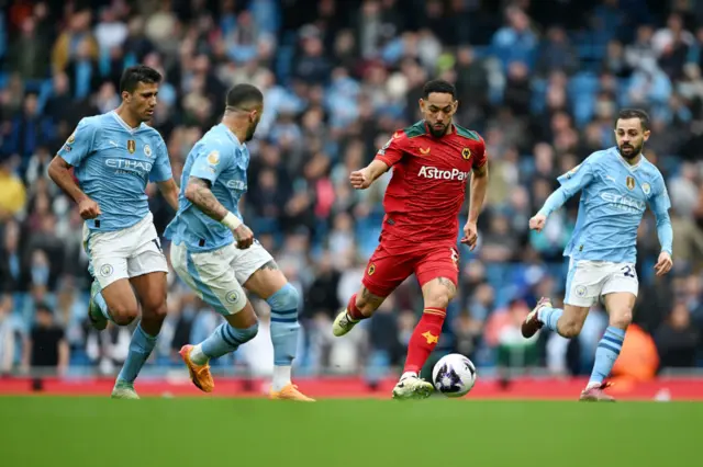 Matheus Cunha of Wolverhampton Wanderers runs with the ball whilst under pressure from Rodri, Kyle Walker and Bernardo Silva of Manchester City during the Premier League match between Manchester City and Wolverhampton Wanderers