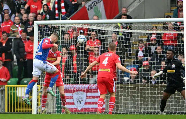 Linfield's Ethan McGee rises to head into the Cliftonville net