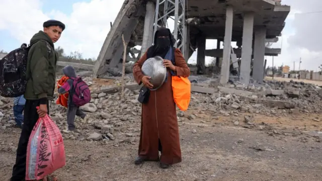 Displaced Palestinians in Rafah in the southern Gaza Strip carry their belongings as they await transportation following an evacuation order by the Israeli army