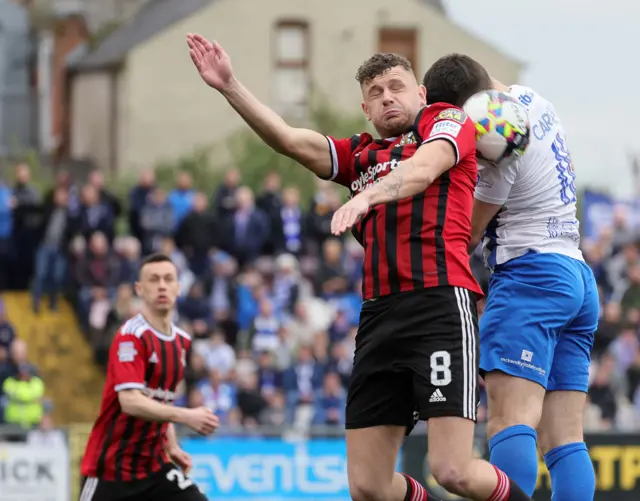 The ball gets caught between Crues midfielder Ben Kenndy and Josh Carson