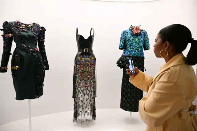 A woman views colorful dresses in a museum