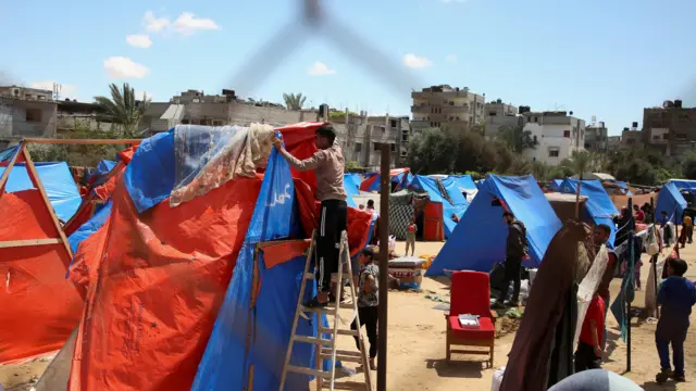 Man stands on top of ladder while dismantling tent