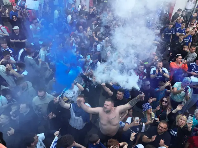 Ipswich Town supporters, including a man with no top on holding a flare