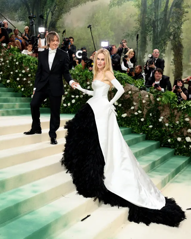 Nicole Kidman in a large black and white ballgown walking up green carpeted steps