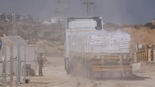 An Israeli soldier stands guard as a truck carrying aid makes its way through the Erez Crossing to Gaza at the weekend