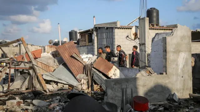 Palestinians inspect the site of an Israeli strike on a house