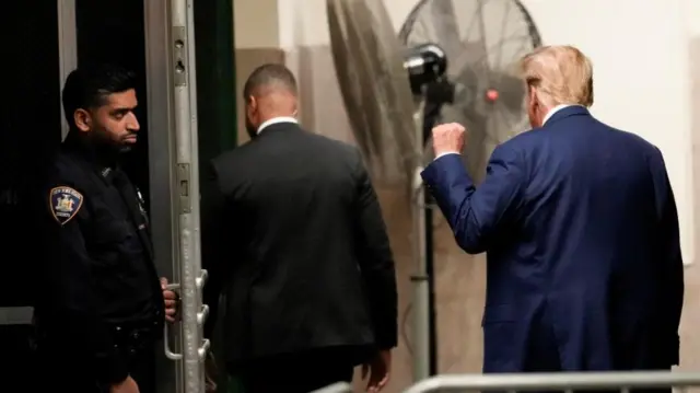 Donald Trump raising clenched fist as he leaves the courtroom.