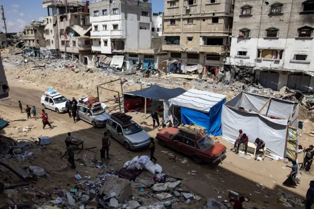 Four vehicles carrying belongings near a series of tents in the city of Khan Yunis.