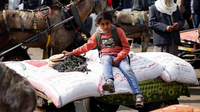 FILE PHOTO: Palestinians gather to receive bags of flour distributed by UNRWA, in Rafah