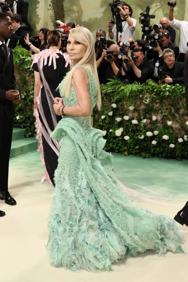 A blonde woman wears a pastel green gown that looks like seafoam