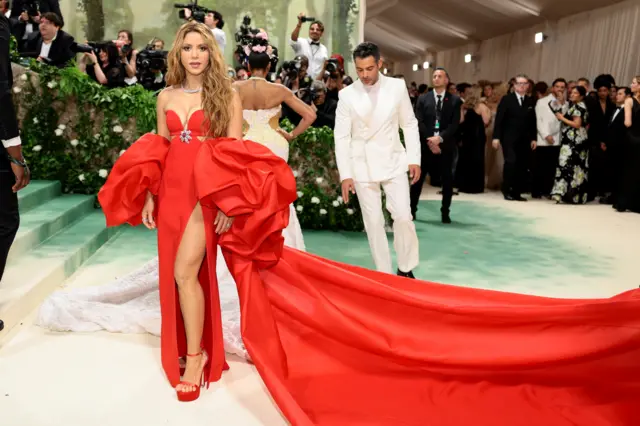 Shakira wears a red gown with voluminous sleeves