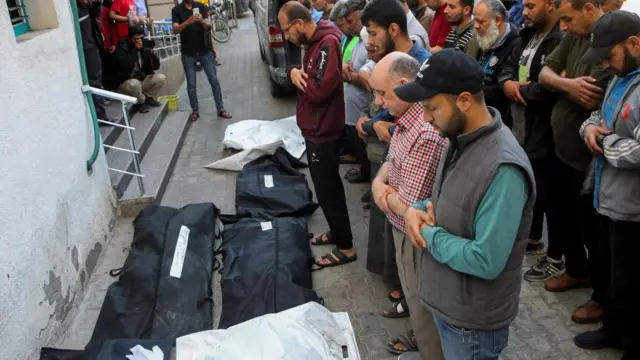 Palestinians pray next to the bodies of people reportedly killed in Israeli strikes in Rafah, in the southern Gaza Strip (9 May 2024)