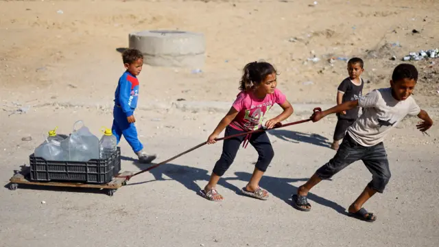 Palestinian children pull water containers as people flee Rafah