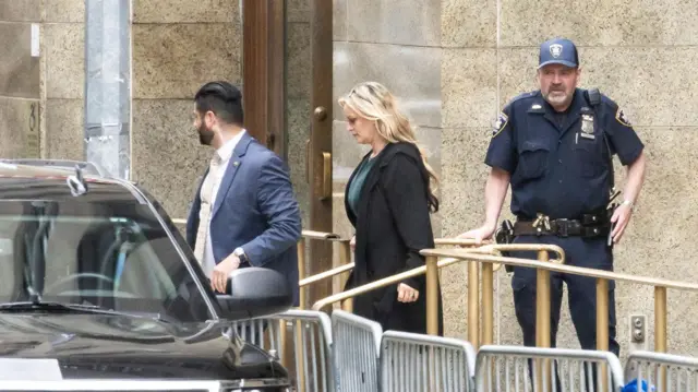 Stormy Daniels leave a New York court while security stands nearby