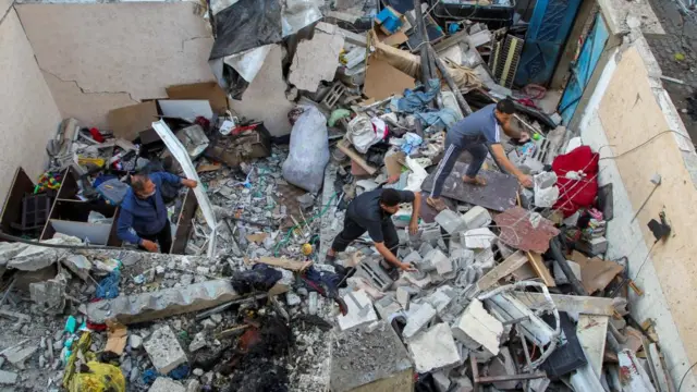 Palestinians inspect a house damaged in an Israeli strike. It is unclear when the airstrike hit the home