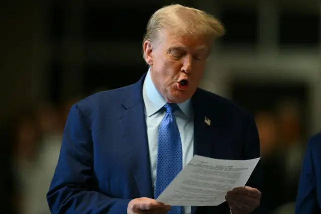 Donald Trump reads from a piece of paper outside court