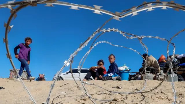 Children sit near belongings in Rafah as people flee the southern city.