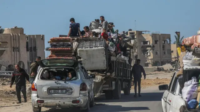 Palestinians crowd into a car and trailer with their belongings piled into the back of the vehicles and strapped to the top.