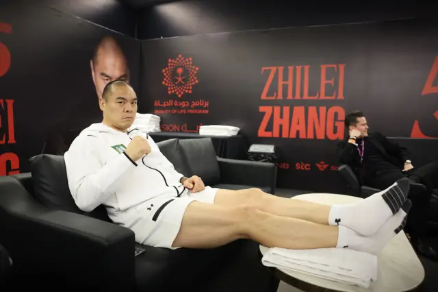 Zhilei Zhang puts his feet up and sits on a sofa