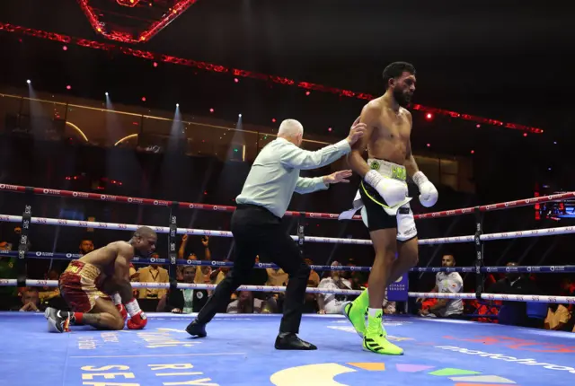 Hamzah Sheeraz is pushed away by the referee with Austin Williams on the canvas