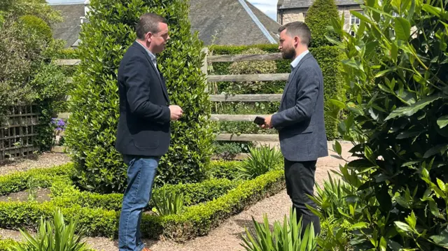 David Wallace Lockhart speaks to Douglas Ross in a garden