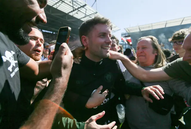 Head coach Fabian Huerzeler of St. Pauli celebrates with fans on the pitch