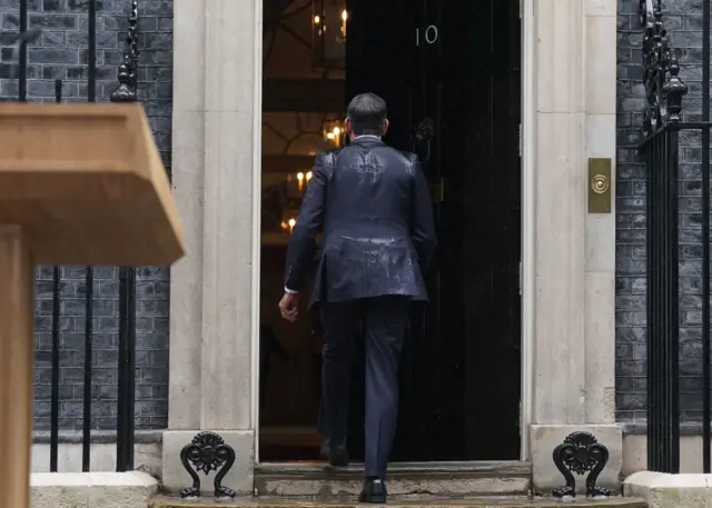 Sunak walks into No 10 in a rain-soaked suit