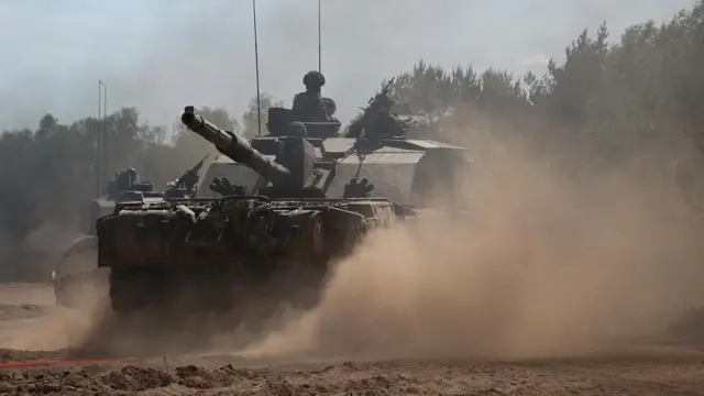 Part of the 12th Armoured Brigade Combat Team ride a Challenger 2 tank during Nato 2024 exercises