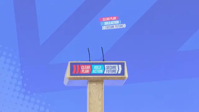 A lectern, emblazoned with the slogan: 'Clear plan, bold action, secure future'