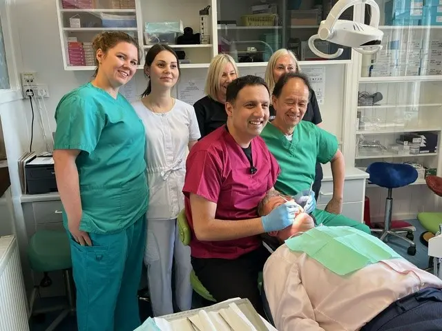 Anas Sarwar examines a man's mouth with dentists behind him