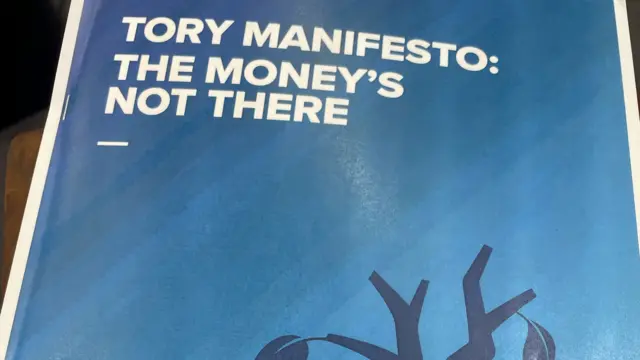 A picture of a Labour pamphlet that says the Conservative Party's manifesto is unfunded, with a picture of the Tory logo with leaves falling off of it.