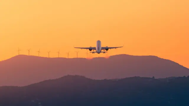 Plane flying into sunset