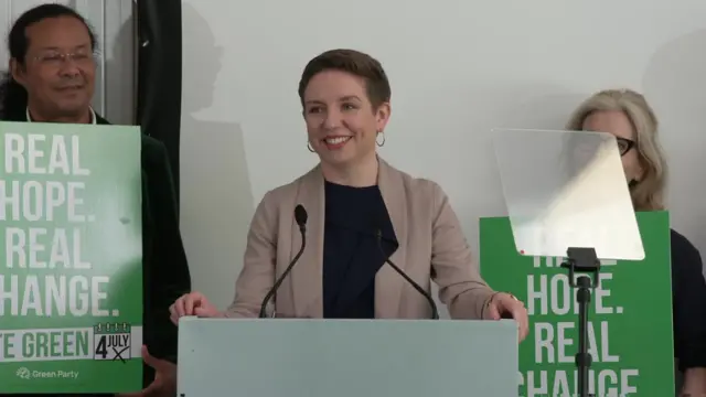 Carla Denyer speaks at a podium while unveiling the Green Party election manifesto.