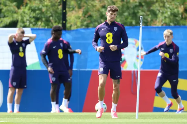 John Stones lightly jogs with other players in the distance