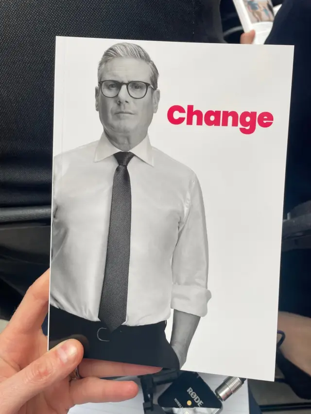 Chris holds the manifesto with a picture of Keir Starmer on the front