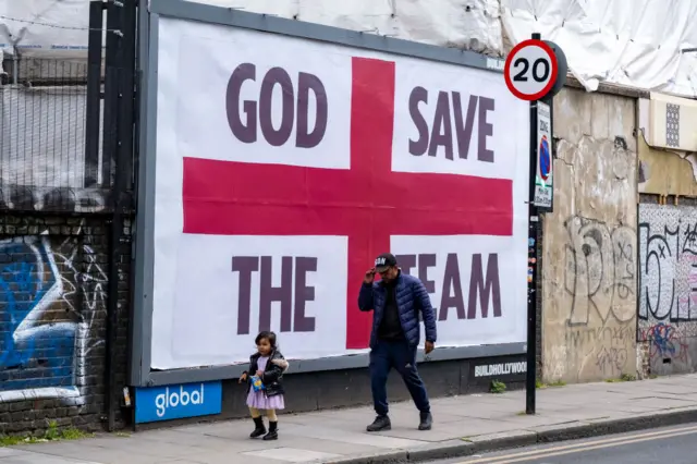 A billboard with words 'God Save the Team' as part of a St. George's flag