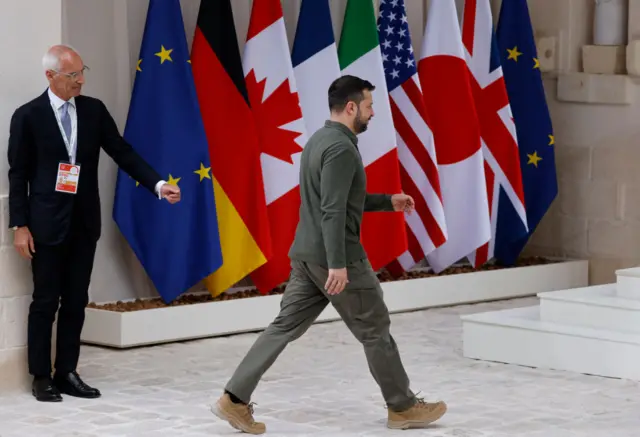 Zelensky in front of flags at the G7 summit