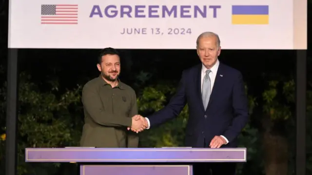 Volodymyr Zelensky and Joe Biden shake hands after signing security agreement